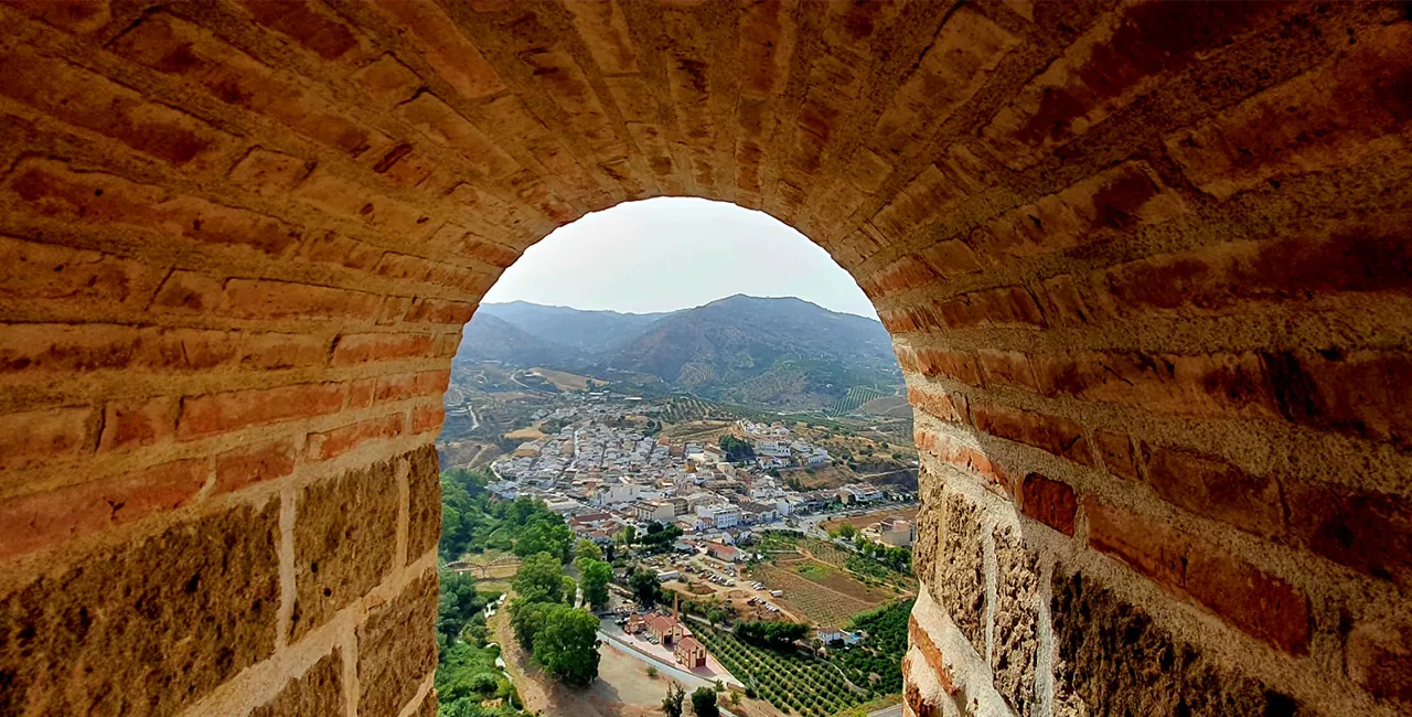 El pueblo de Álora y su valle vistos a través de un arco de ladrillo del castillo